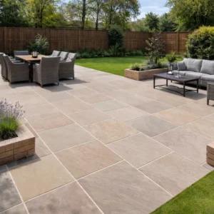 A spacious backyard patio features Raj Green Indian Sandstone Paving Slabs (Handcut, 22mm Calibrated, 600x600mm), complemented by outdoor dining and lounge furniture, potted plants, green lawn, wooden fencing, and landscaped hedges.