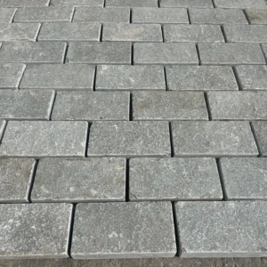 Grey Limestone Sawn Edged Setts (200mm x 100mm x 40mm) are laid in neat, staggered rows. Their subtle color and texture variations create a natural, rustic look for paved surfaces.