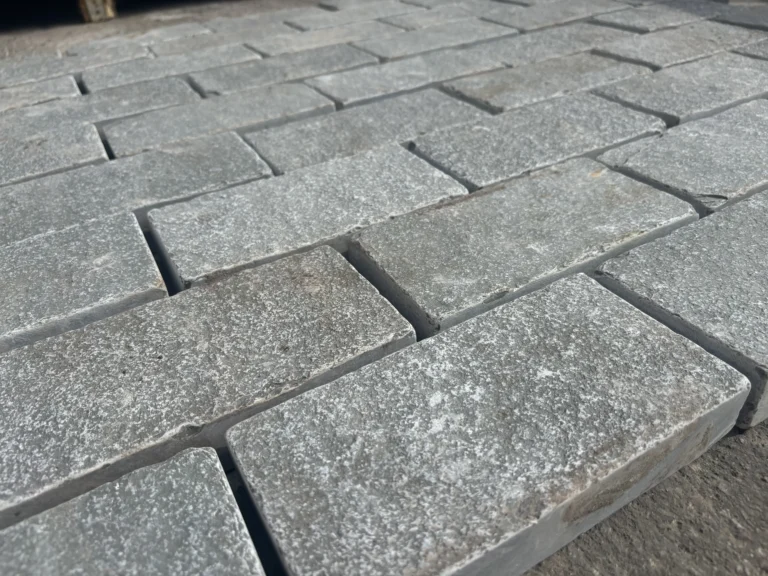 Close-up of Grey Limestone Sawn Edged Setts (200mm x 100mm x 40mm - Sample) arranged in neat rows, creating a flat surface. The setts feature a rough texture and subtly varied grey tones.