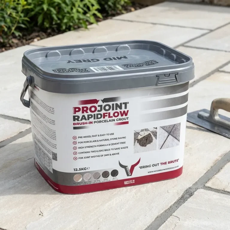 A rectangular tub of Nexus Brush-In Porcelain Paving Grout sits on a paved outdoor surface, surrounded by paving stones and a trowel. The tub features a gray lid and detailed product information on its label.