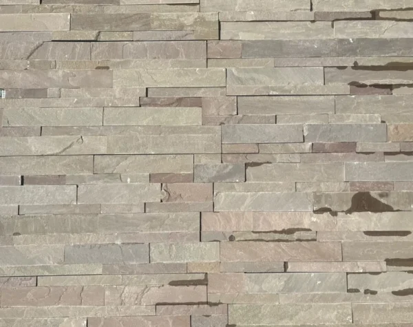 The Raj Green Stone Cladding displays rectangular slabs in a textured stone wall, showcasing a mix of beige, brown, and gray hues arranged in an irregular pattern reminiscent of cobble setts.