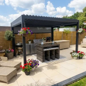 A modern outdoor patio with a black pergola, wicker furniture, a stainless steel grill, bar stools, and hanging flower baskets. Potted flowers and a wooden privacy fence complete the space under a partly cloudy sky.