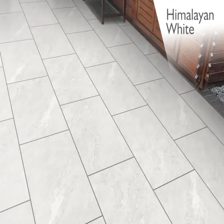 A patio featuring large, rectangular tiles in a soft gray, nearly white hue offers a sleek and contemporary appearance with a subtle texture. In the background, you can see a wooden fence. The words "Himalayan White Outdoor Porcelain Paving Tiles - 600mm x 900mm x 20mm" are displayed in the top right corner.